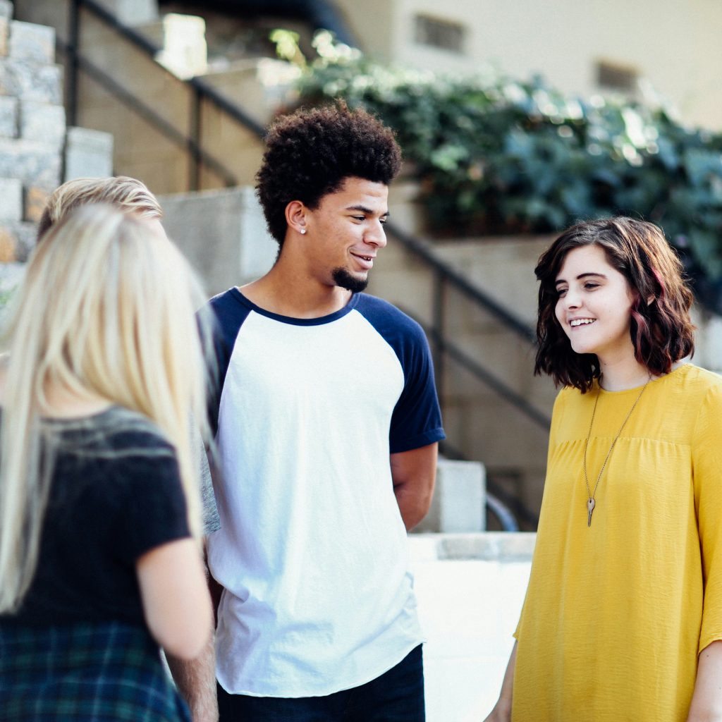 A photo of three Teenagers chatting and smiling on a high street.