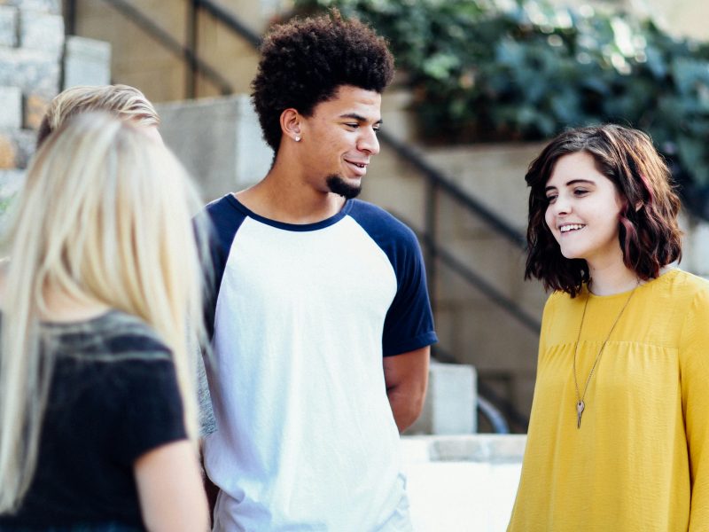 A photo of three Teenagers chatting and smiling on a high street.