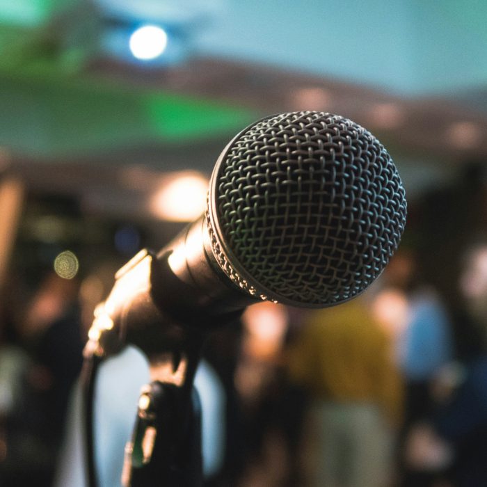 A photo of a microphone with a blurred background suggesting an audience.